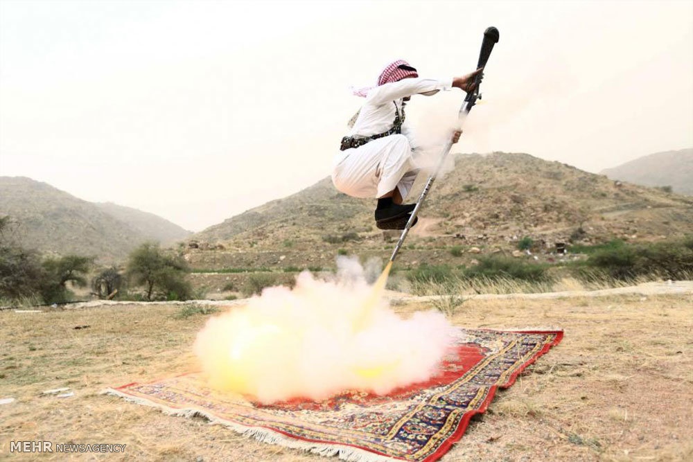 گزارش رویترز از سنتی عجیب در عربستان/ پریدن با تفنگ از روی آتشی که روی فرش ها روشن شده