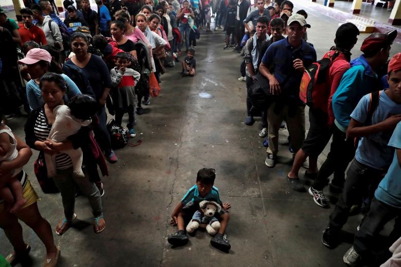 یک کودک در میان مهاجران هندوراسی که سعی دارند به آمریکا بروند، بر روی زمین نشسته است