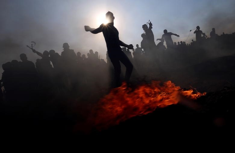 تظاهرکنندگان فلسطینی در اعتراض به حق بازگشت به وطننشان به نیروهای اسرائیلی در نوار غزه سنگ پرتاب می کنند