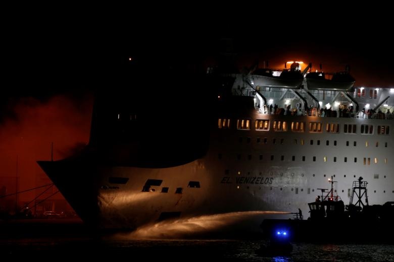 آتش‌نشانان تلاش می‌کنند حریق یک کشتی در بندر پیرئاس یونان که از آن دود بلند می‌شود  را مهار کنند