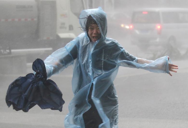 یک زن در طوفان مانگکوت چین می دود