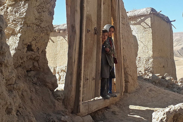 تصویردو کودک افغانی در آستانه دری که تا 2روز پیش به دیوار خانه شان چسبیده بود